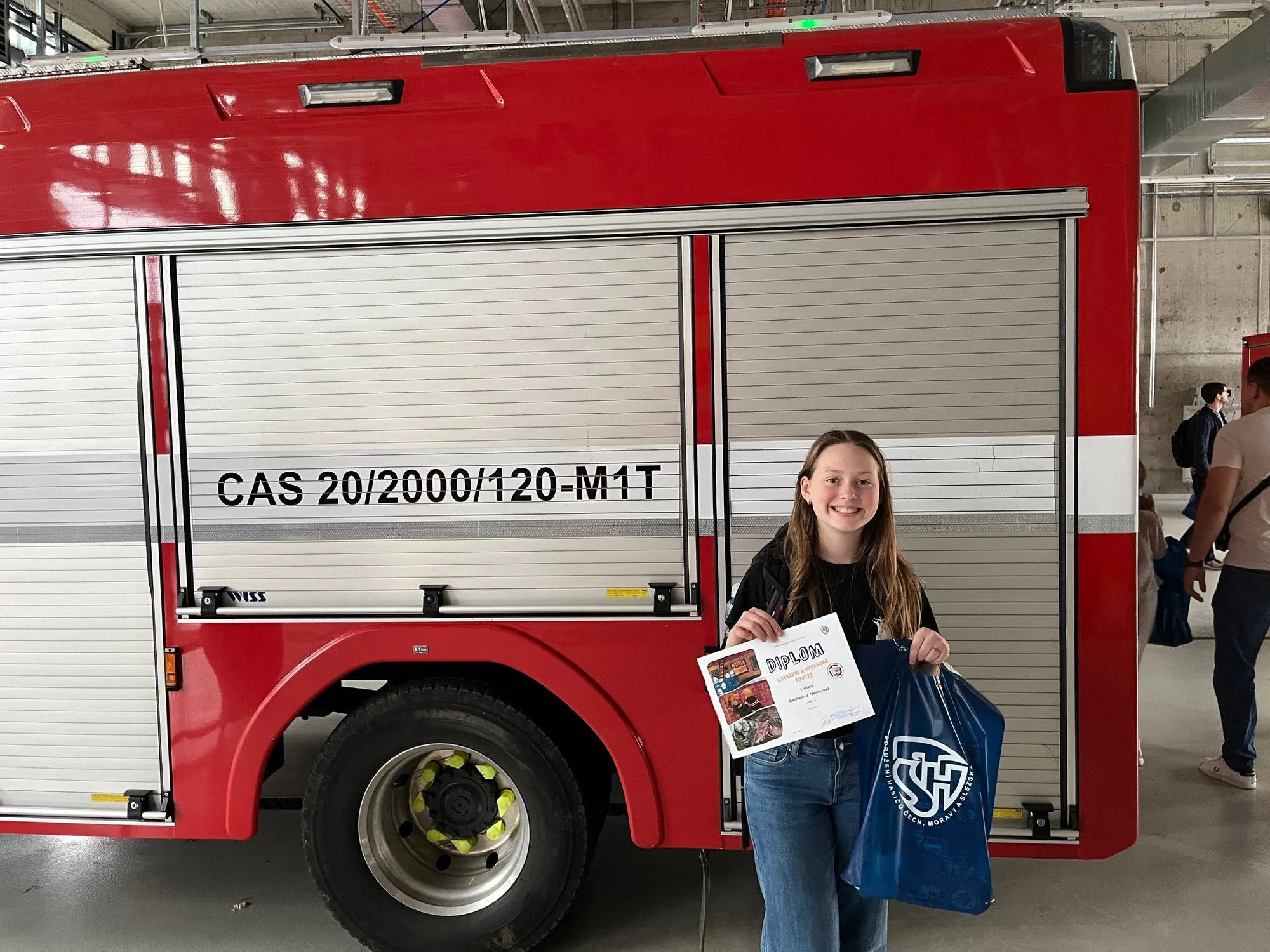 Magdaléna holding her Fire Protection Through Children’s Eyes award beside a fire engine
