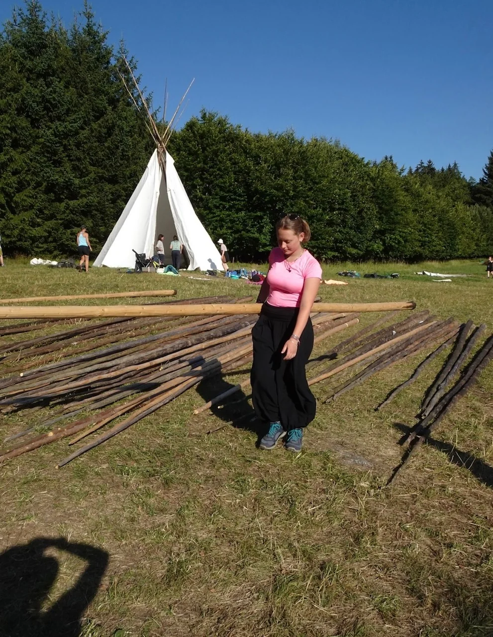 A Scout standing beside wooden poles and a canvas tent
