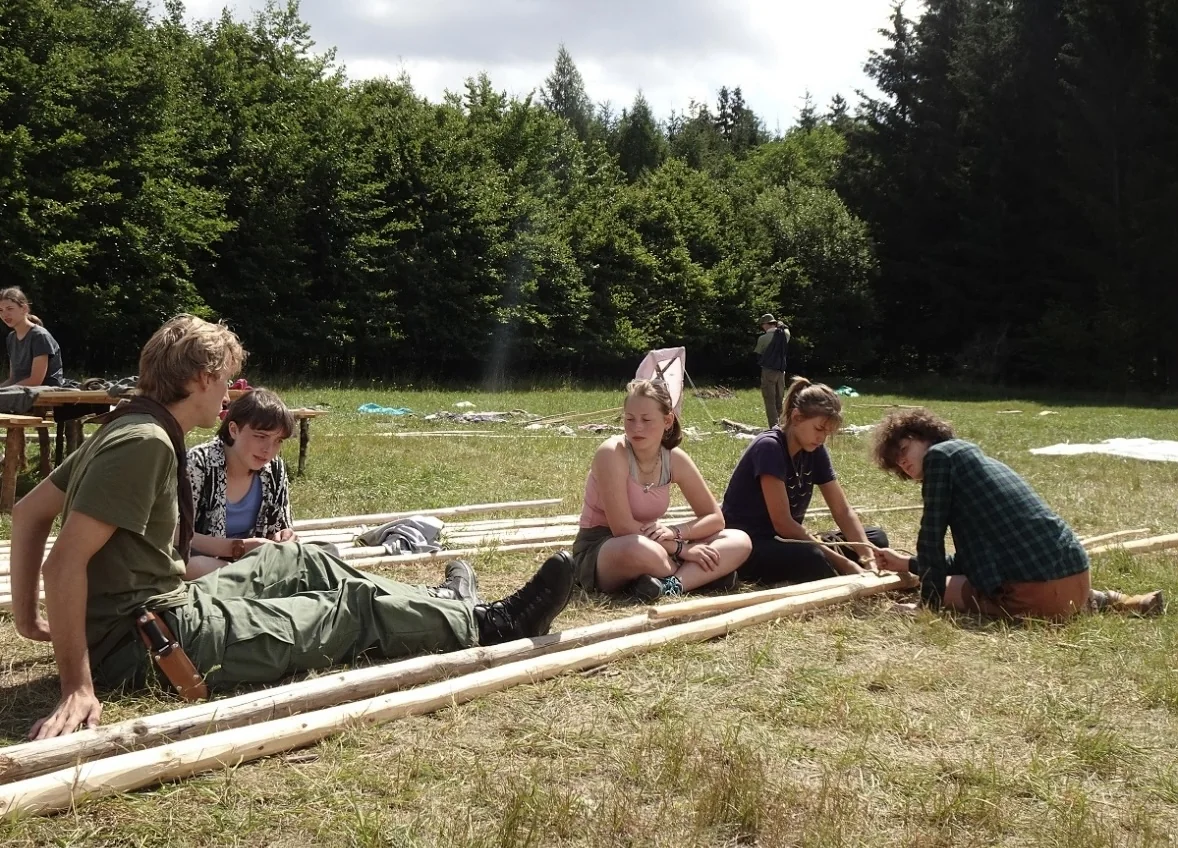 Scouts assembling wooden poles together in a meadow
