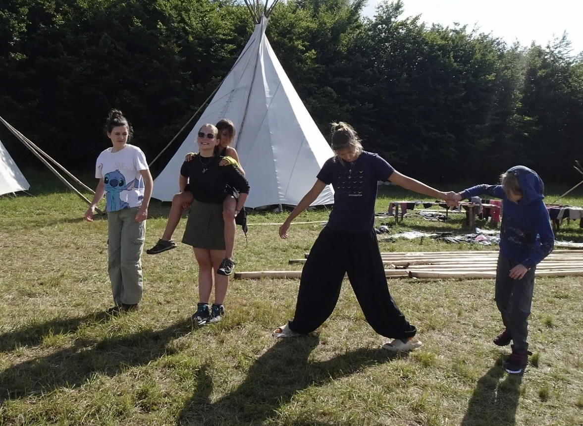 Scouts holding hands during a group activity beside a canvas tent