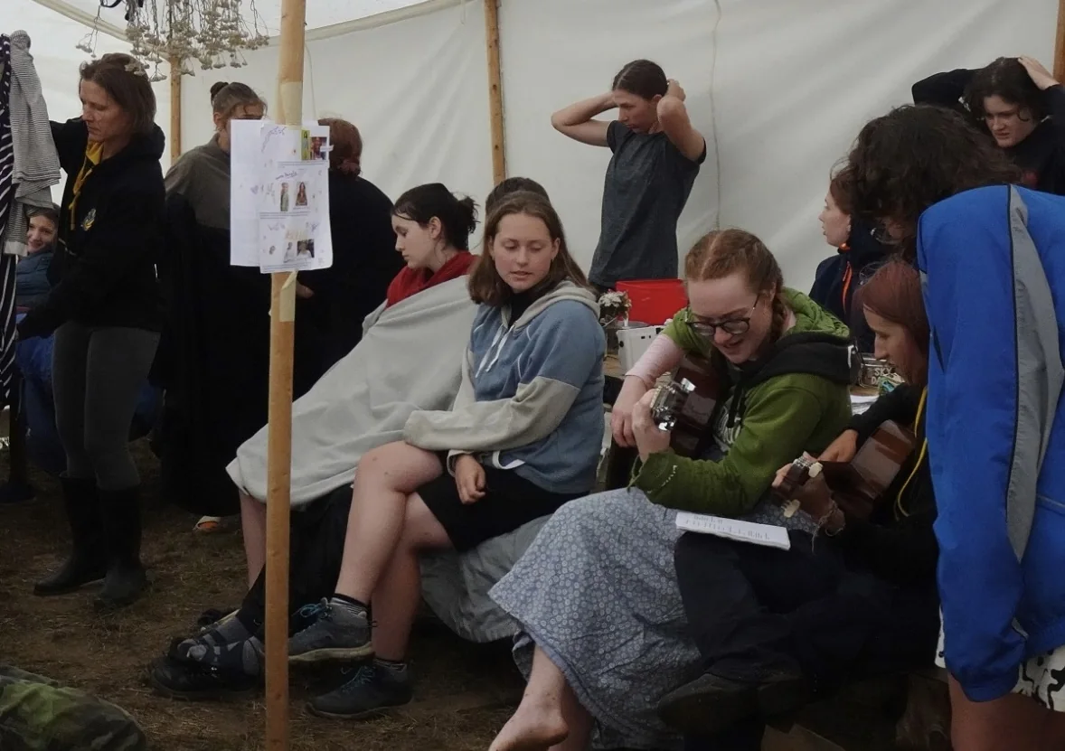Scouts spending time together inside a tent while it rains outside