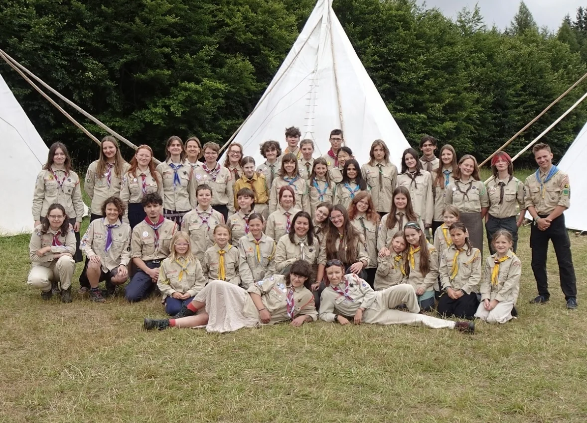 A large Scout group posing in uniform in front of canvas tents