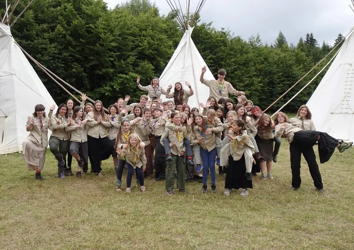 A large Scout group together in uniform between canvas tents