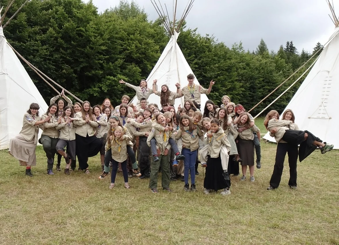 Scouts posing playfully together in a camp meadow