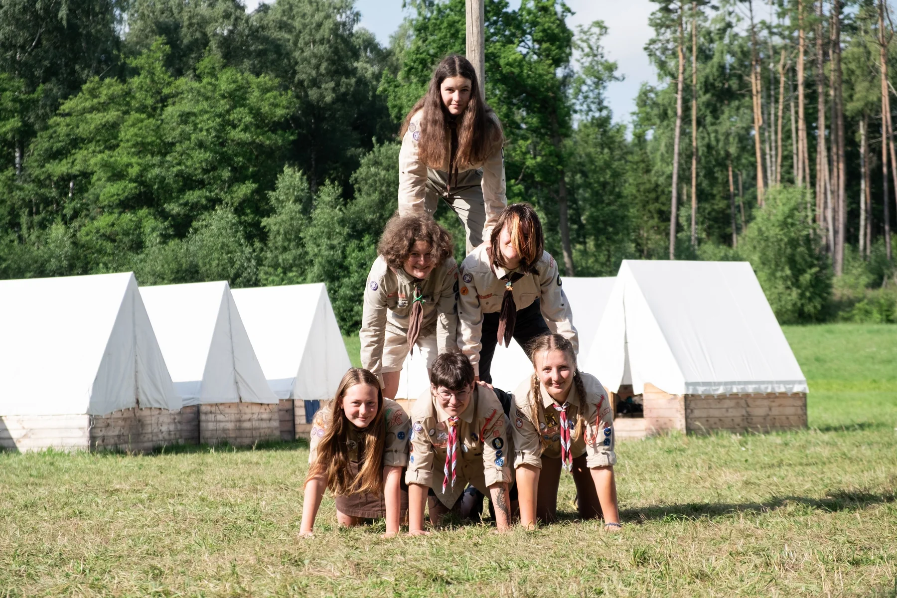Friends making a playful human pyramid at summer camp