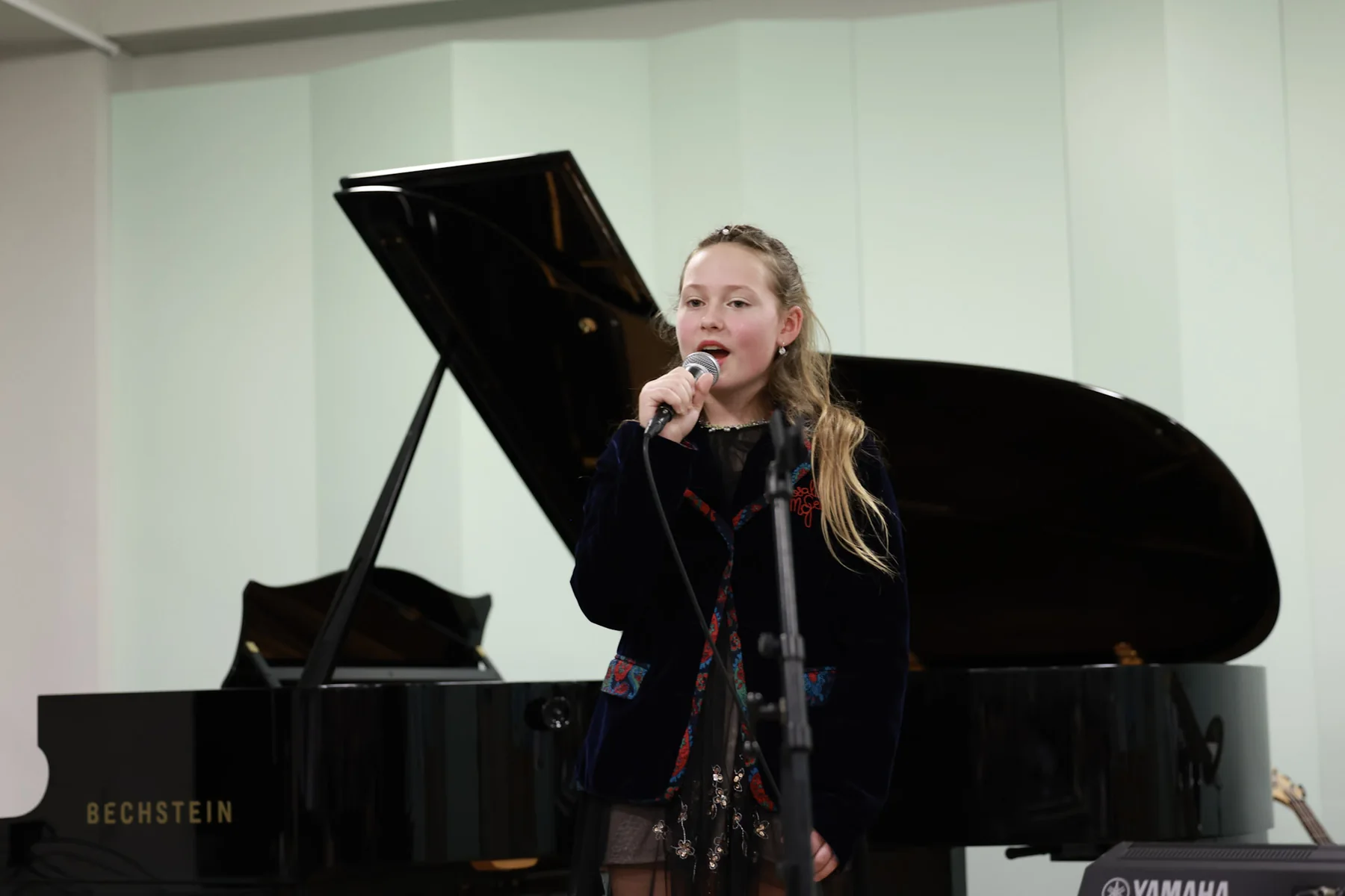 Magdaléna singing beside a grand piano